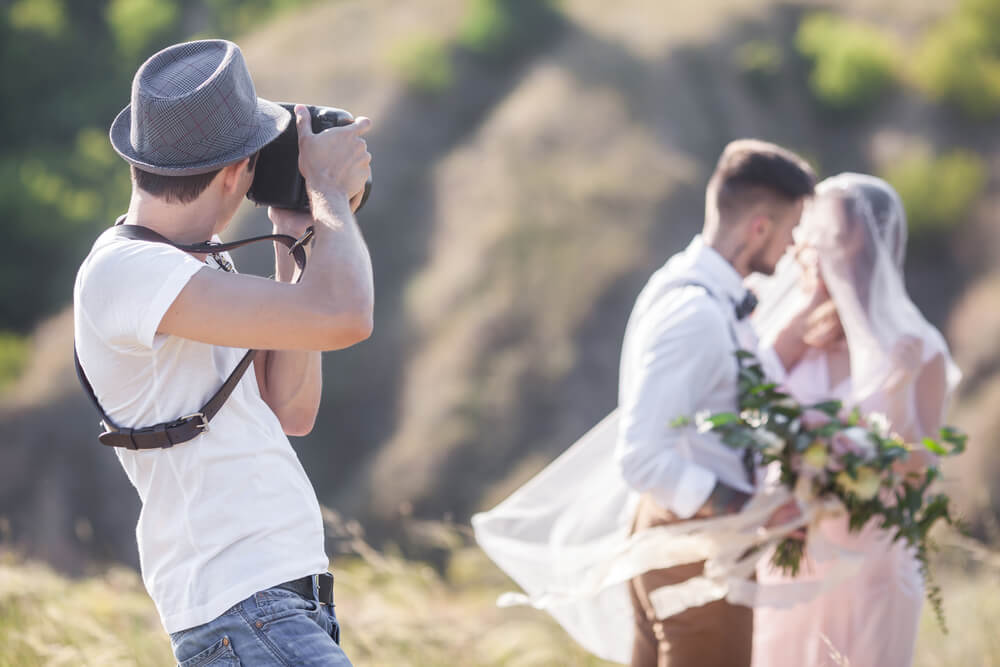 A wedding photographer in Estes Park shooting a photo of a newlywed couple embracing