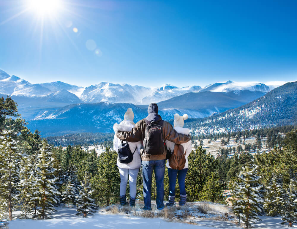 A family admiring the Rocky Mountains on a hike in Estes Park, one of the best things to do in the area in winter