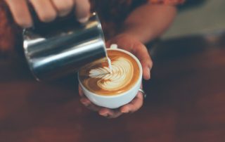 A barista pouring a cup of coffee at an Estes Park coffee shop