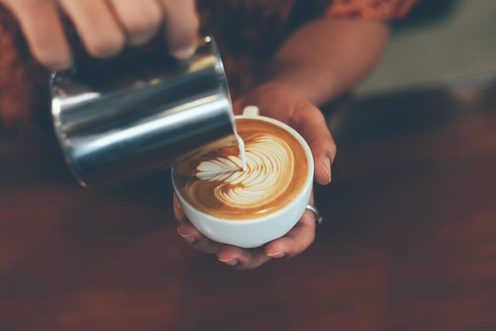 A barista pouring a cup of coffee at an Estes Park coffee shop