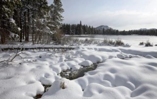 Snow covering the banks of a lake in Estes Park during the winter