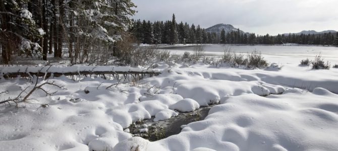 Snow covering the banks of a lake in Estes Park during the winter